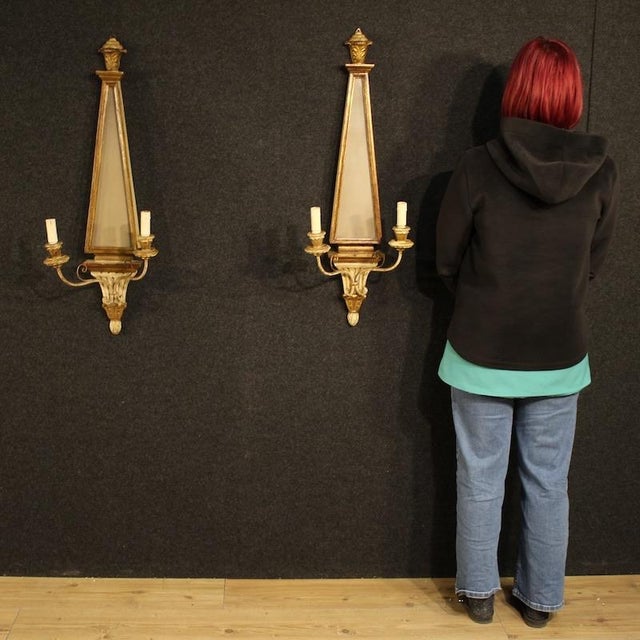 A pair of mid-20th-century Italian wall lights. Louis XVI-style furniture in wood, glass, and iron, carved, lacquered, and...