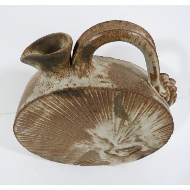 Unique studio pottery rustic stoneware ewer in a flattened disc shape with sharp edges. This vessel has an incised...