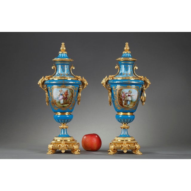 Pair of covered polychrome porcelain vases in the style of Sèvres with gilt bronze mounts. The base stands on four claw...