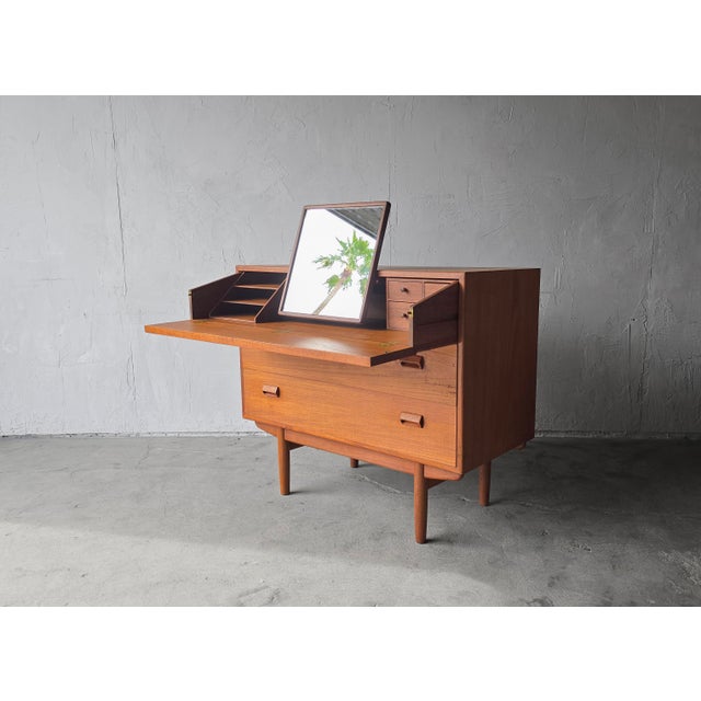 This Danish modern dresser–vanity features classic mid-century lines in warm teak with tapered legs and recessed pulls....