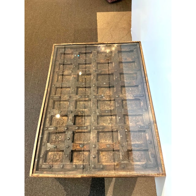 Stylish Antique Indian Wood & Iron Carved Door Cocktail Table. Carved wood details with glass top. Showroom Floor Sample.