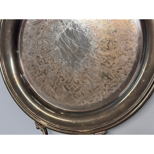 Design Plus Gallery presents a Vintage Silverplate Engraved Round Handled Tray. The circular form has a raised rim, two...