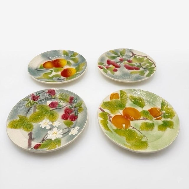 These four antique Saint-Clément majolica plates, dating from the 1950s/60s, celebrate garden fruits with the decorative...
