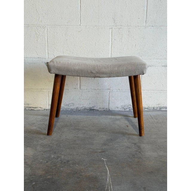 This charming accent ottoman features a neutral beige fabric cushion supported by slender tapered walnut legs. Its compact...