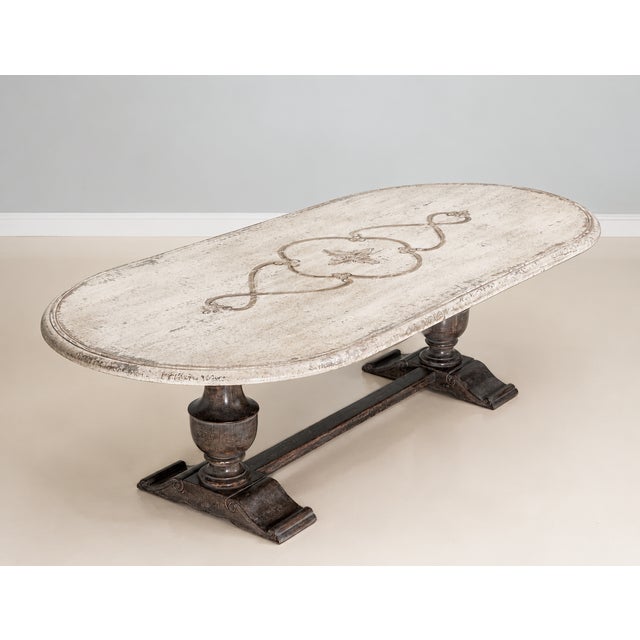 Handcrafted in Italy, this oval dining table features an antique white finish with subtle grey undertones and hand-painted...
