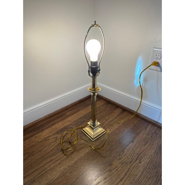 A timeless polished brass table lamp featuring a classic column form and stepped square base, embodying refined...