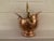 Copper helmet coal scuttle with brass swing handle. Handle attached with brass lion head on each side. Has a rear handle....