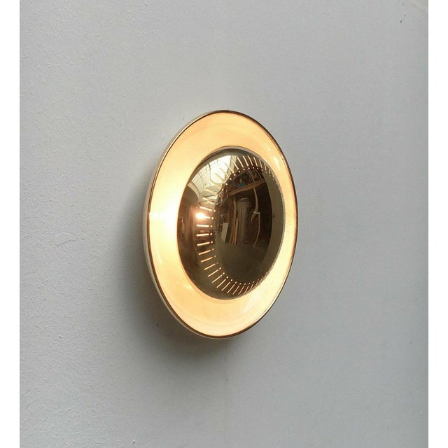 Imposing Mid-Century wall lamp. The lamp consists of two parts. The curved reflector trough and the shiny front element....