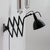 Articulating black enameled metal scissor wall lamps by Kandem, extends from 14″ to 50″, hood enameled white interior.