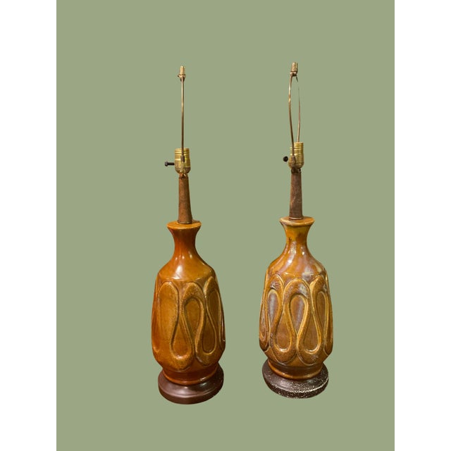 Mid century ceramic table lamps. It’s a mustard brown color with patina glazes on raised curvature vase with a wood...