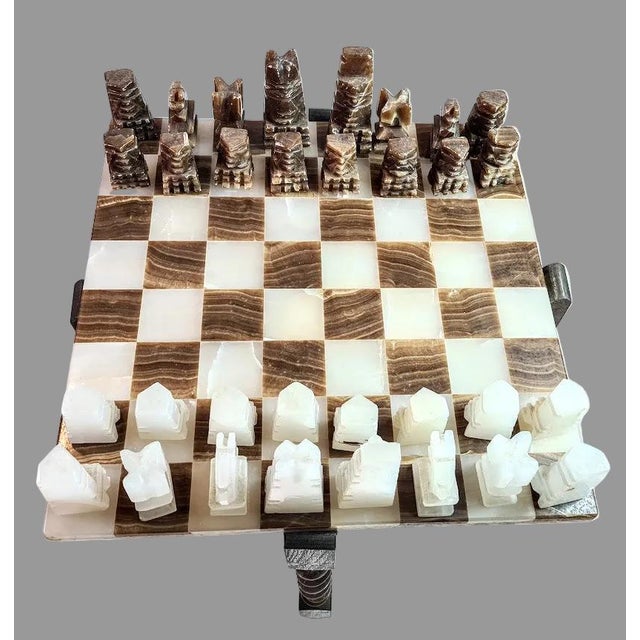 This chess board table features a rare and distinct handcrafted onyx and marble pieces on a Jacobean style folding frame....