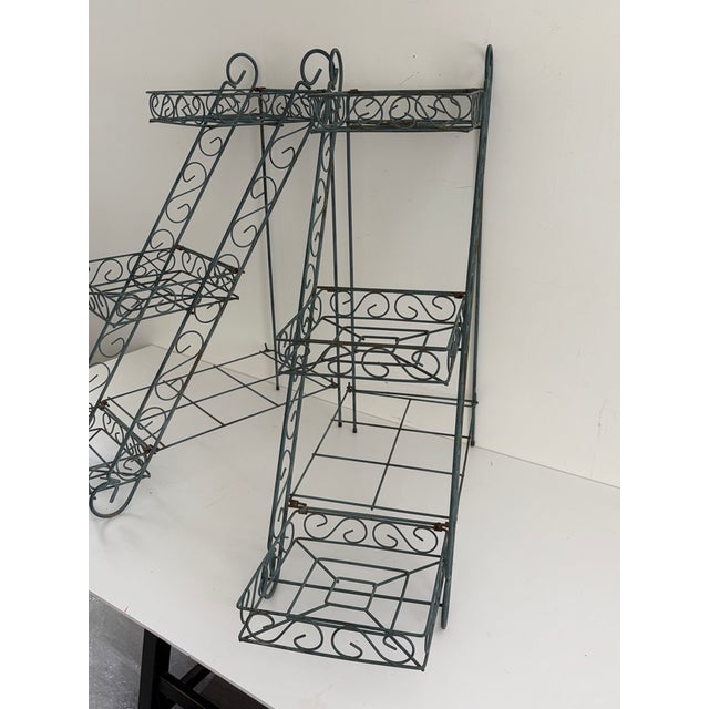 Pair of matching three-tier wrought iron plant stands with openwork scroll design. Each stand has three basket-style...