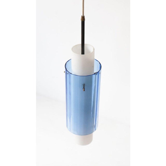 This pendant lamp was designed and produced in Italy in the 1950s. It is made from glass, opaline glass, iron and brass....