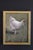 This watercolor on paper depicts a solitary white chicken, rendered with delicate brushwork that captures its soft...