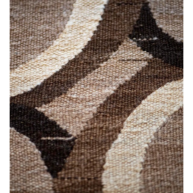 This handwoven flatweave rug has a shaded mole-brown field with an overall design of chocolate-brown, charcoal-brown and...