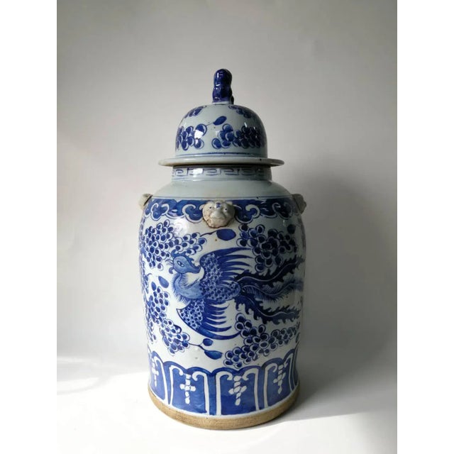 This blue and white porcelain jar is adorned with hand painted flying phoenix. The lid has a small foo dog on top. There...