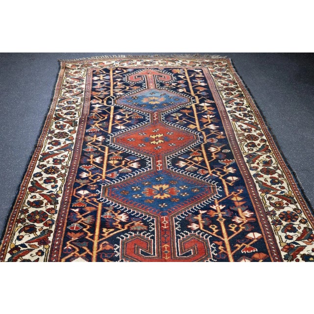 The navy-black field displays a lavishly hooked pole medallion of three hexagons in red and abrashed light/medium blue,...