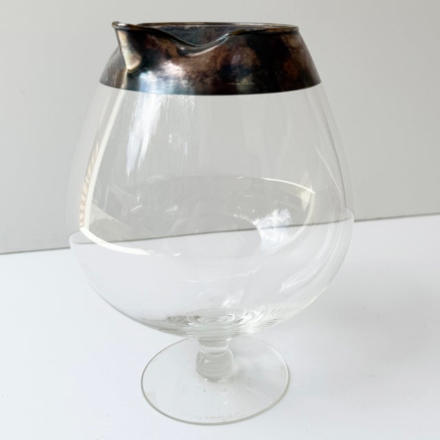 A classic mid-century cocktail pitcher with sleek silver rim. A perfect addition to your home bar.