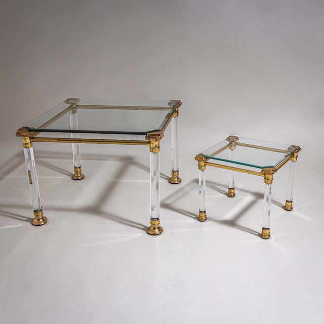 Two coffee tables of square form with faceted column legs featuring stylized brass capitals and bases. The tabletops are...