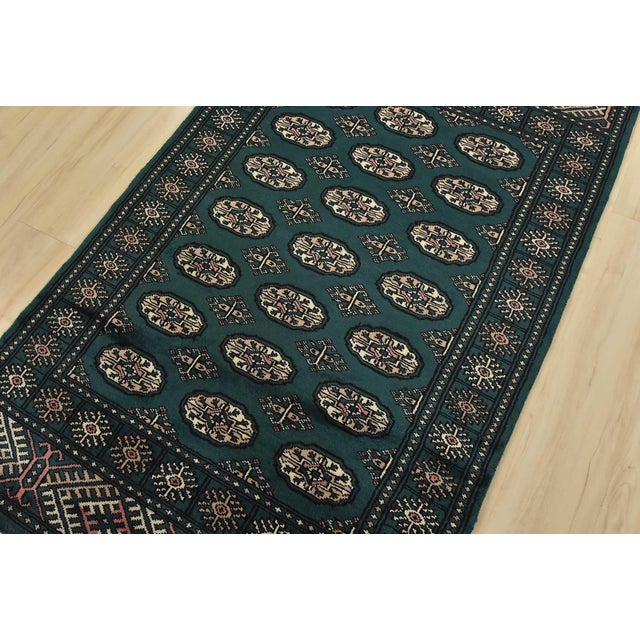 A tribal Bokhara rug hand-knotted with an all-wool pile on a cotton foundation. This finely woven oriental rug features...