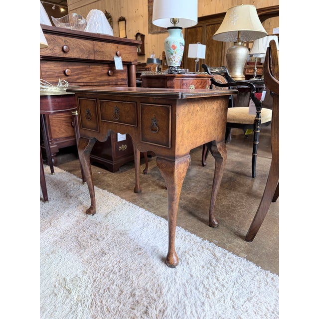 A distinguished early 20th century Queen Anne lowboy showcasing beautifully figured burl walnut veneers and graceful...
