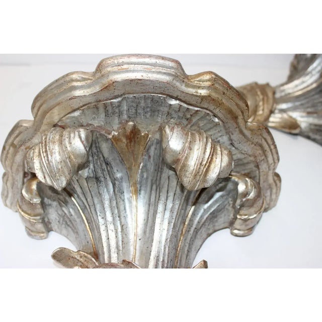 Stylish pair of Italian Louis XV style wall brackets are hand-carved wood in Italy with a silver leaf and gold tipped finish.