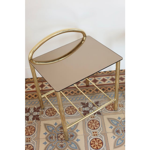 Pair of vintage 1970s bedside tables with an elegant, graphic design, featuring a tubular gold metal frame and a smoked...
