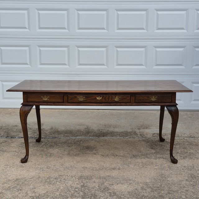 This is a beautiful late 20th century Pennsylvania House Queen Anne style stained oak library table or desk. The table...
