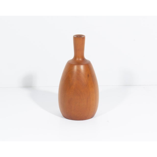 A turned wood vase signed "Kinzer." This vase features an elongated and bulbous shape, with a narrow opening. It is signed...