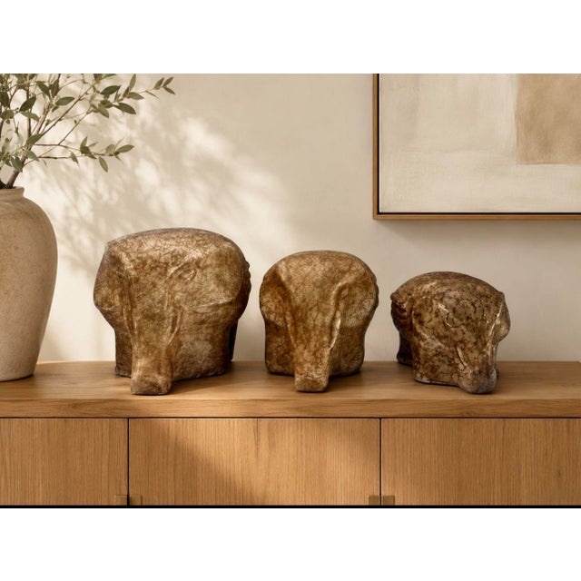 Charming graduated set of three vintage ceramic elephant sculptures with a warm beige and brown marbled finish. Each...