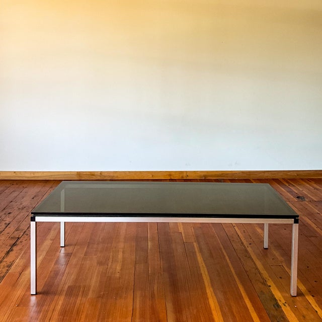 This Florence Knoll style coffee table features a minimalist chrome frame and a smoked glass top. Glass is in good shape...