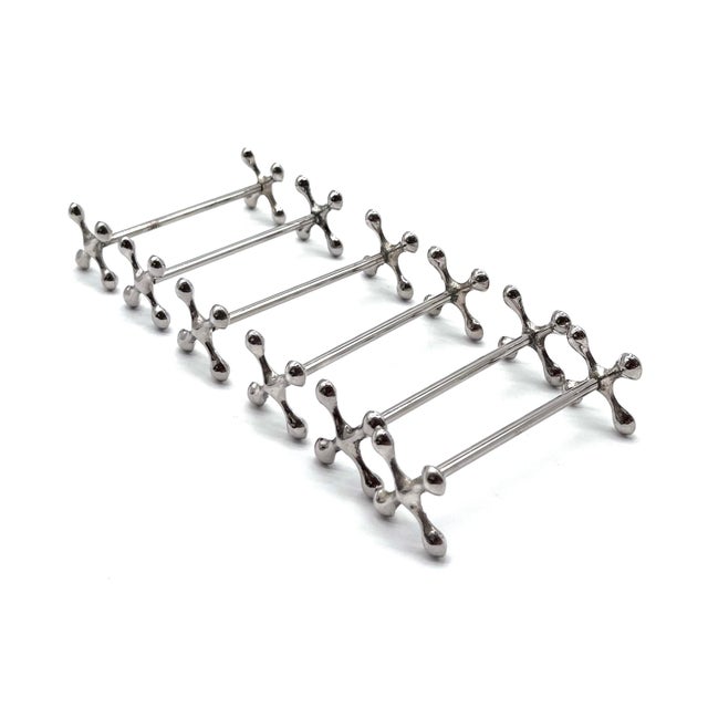 This set consists of six elegant, silver-plated knife rests. The unique, stylized cross design (also known as an "X"...