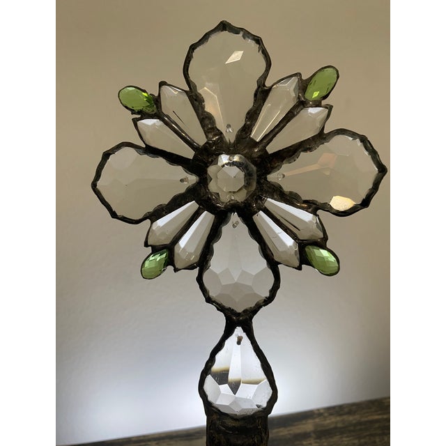 This one-of-a-kind assemblage sculpture pairs an embossed clear glass flask bottle with a handcrafted floral-cross topper...