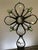 This one-of-a-kind assemblage sculpture pairs an embossed clear glass flask bottle with a handcrafted floral-cross topper...