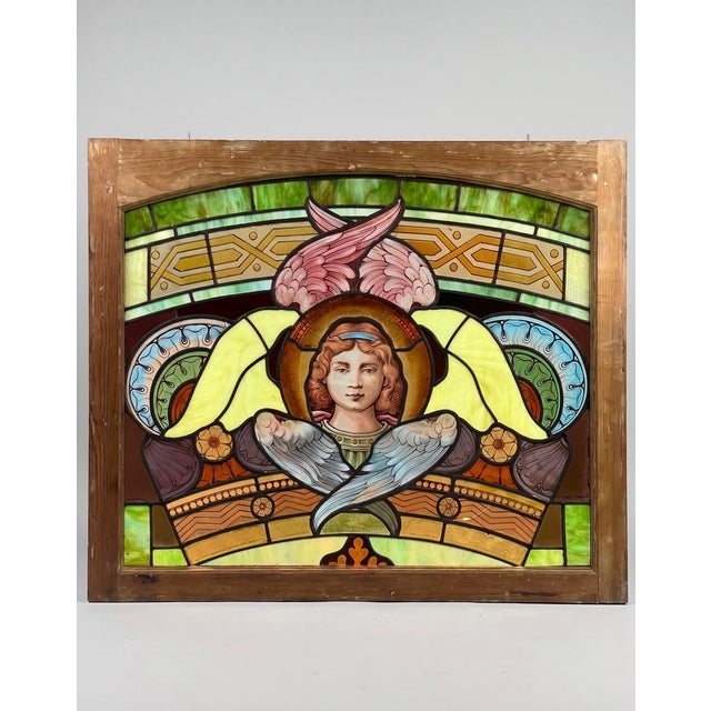 Victorian era stained glass window with a hand-painted central angel portrait in original wood frame, late 19th century. A...