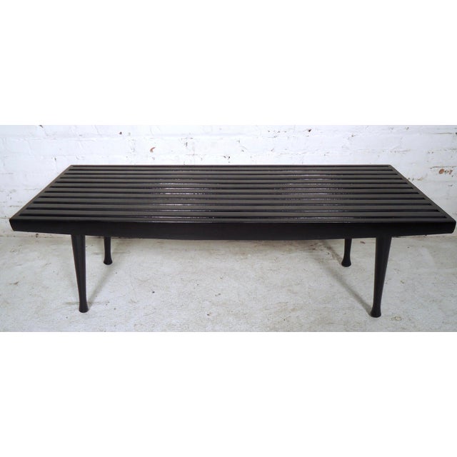 Mid-Century Modern black lacquered slat bench featuring tapered legs. This bench can also be used as a coffee table, would...