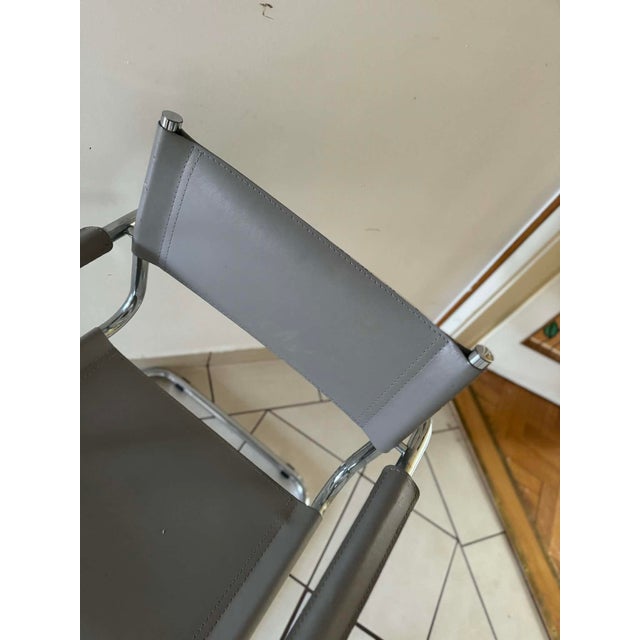 A stylish mid-century modern tubular chair from the 1960s, featuring a sleek chrome frame and comfortable grey upholstery....