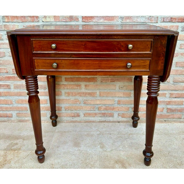Elegant Spanish drop-leaf side table crafted from wood, featuring two practical drawers with round metal handles and four...