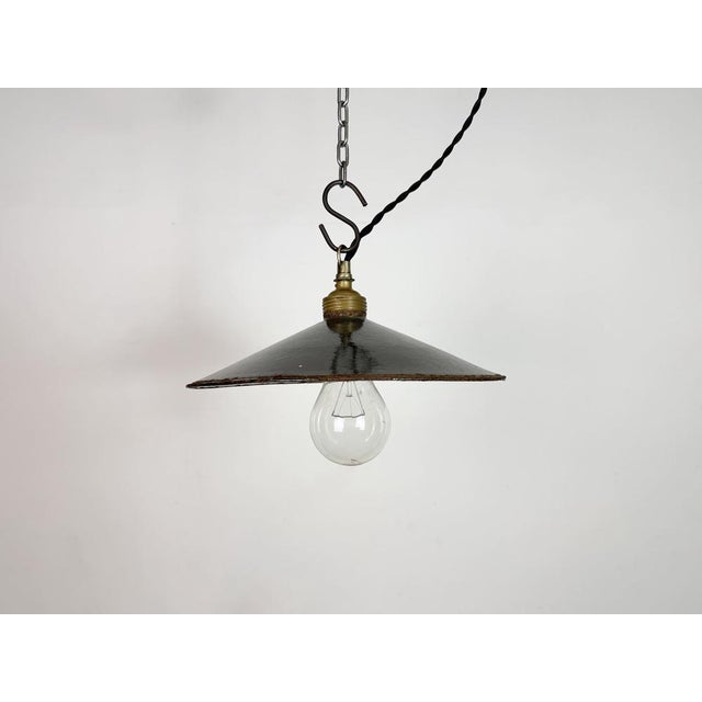 Vintage industrial enamel pendant lamp from the 1930s. It features a rusty black enamel shade with white enamel interior...
