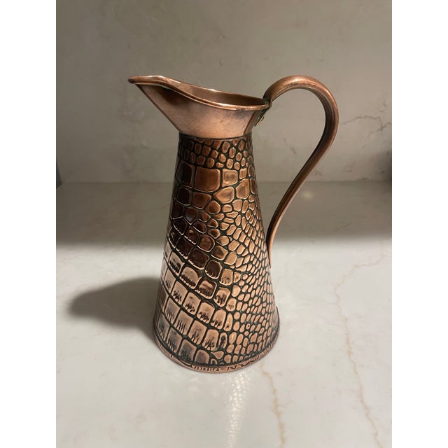This pitcher is from the Arts and Crafts period in the form of faux crocodile skin. These were produced by Joseph Sankey...