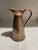 This pitcher is from the Arts and Crafts period in the form of faux crocodile skin. These were produced by Joseph Sankey...