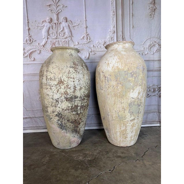 A striking pair of monumental terracotta urns crafted in the Spanish Colonial style, reflecting the rustic elegance and...