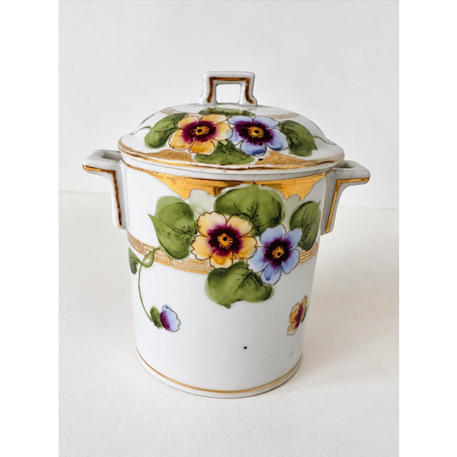Lovely handled lidded jar with hand decorated floral pattern and painted gilt details. Crafted from bone china. Vase does...