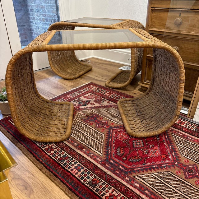 Pair of wicker-wrapped metal-framed side tables from the 1970s. Waterfall shape, natural color, original smoked glass. In...