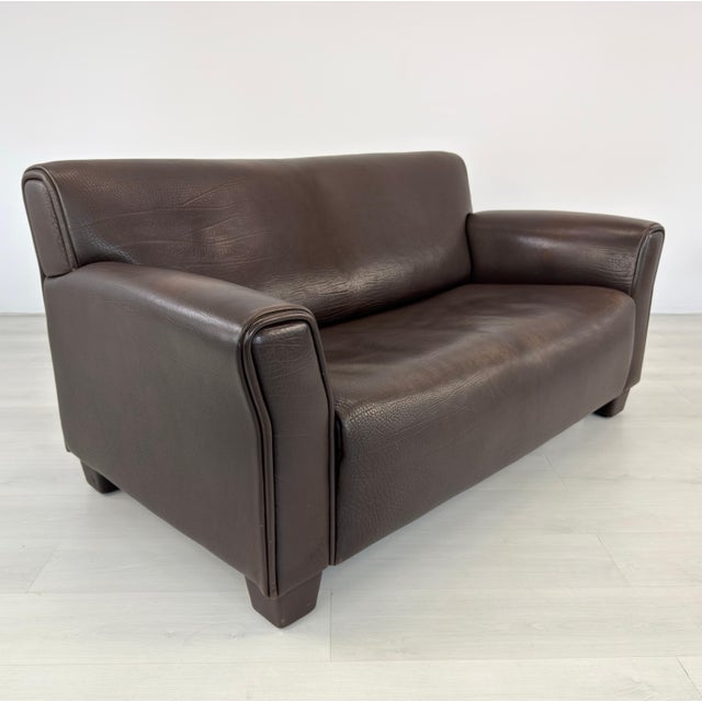 Dimensions: H 32” x W 62.5” x D 34” x SH 17” Vintage Ds 97 brown leather two-seater sofa from De Sede. Produced in...