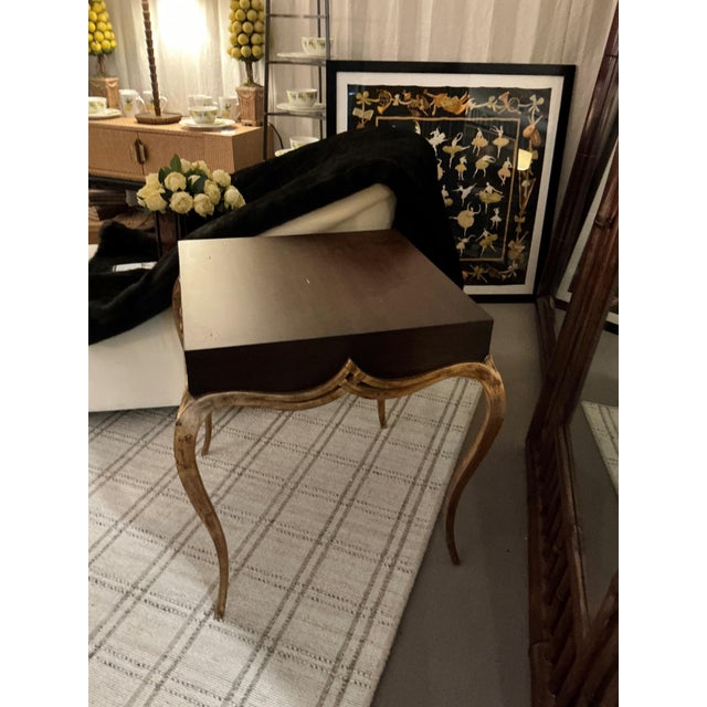 Sculpted side table with a deep mahogany finish top paired with curved legs in a gilt finish. Purchased with “Christopher...