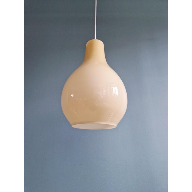 Scandinavian bulb-shaped pendant light in light yellow opaline glass, 1960s. The pendant has been rewired and is...