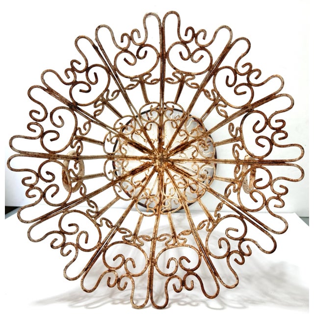 An unusually sculptural vintage wrought-iron planter with elaborate scrolling wirework and a dramatic flared tulip...