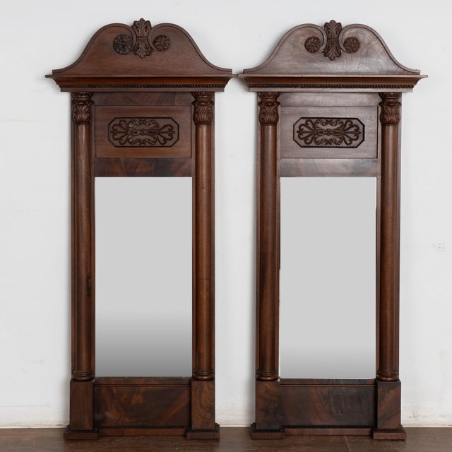 Pair of mahogany mirrors from Denmark, circa 1840-1860, with a carved and scrolled pediment and turned side columns. This...