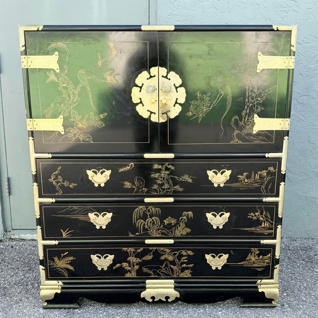 Striking Chinese Chinoiserie armoire and chest of drawers finished in glossy black lacquer with intricate hand-painted...